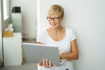 frau steht im büro und schaut auf ihren laptop