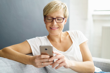 entspannte frau auf dem sofa schaut auf ihr handy © contrastwerkstatt