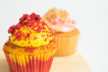 Close up of red velvet and strawberry cupcakes on wooden plate in white background