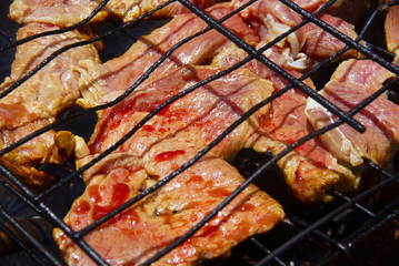 Closeup of some meat slice being grilled half cook in a barbecue