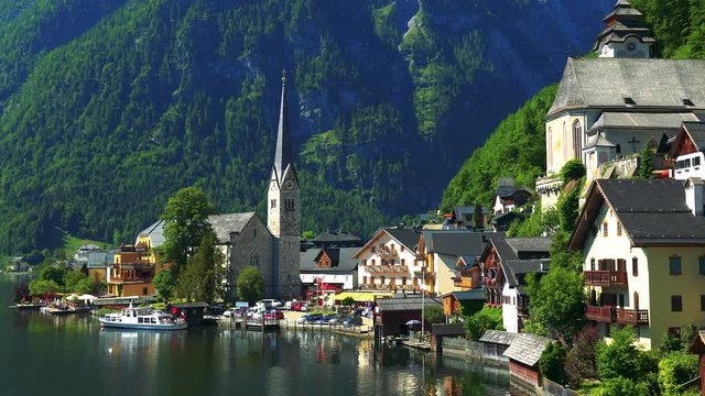Village Hallstatt with church in summer day - mountains and forests in the background
