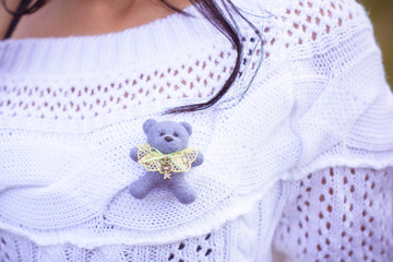Obraz na płótnie Canvas White knitted jumper with a small felt teddy bear handmade brooch