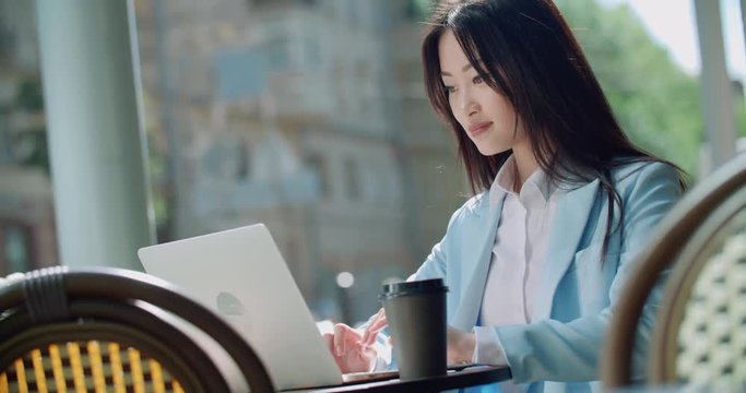 beautiful young successful Asian business girl a freelancer with a laptop in a cafe working on laptop