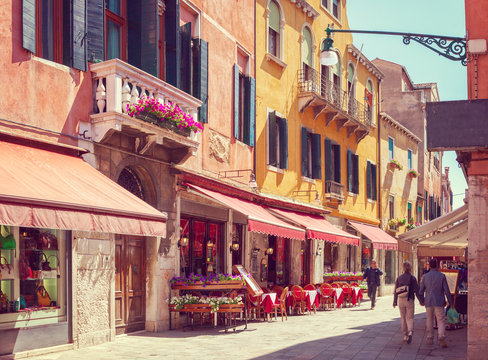 Fototapeta Colorful cozy street with tables of cafe at  a sunny morning, Venice, Italy.    Toned image