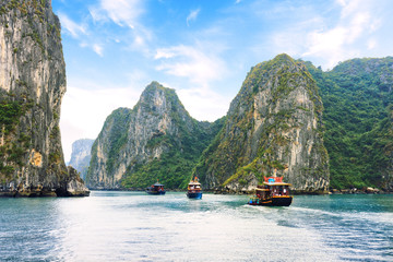 Fototapeta na wymiar Tourist junks floating between limestone karsts and isles in Ha long Bay, Vietnam
