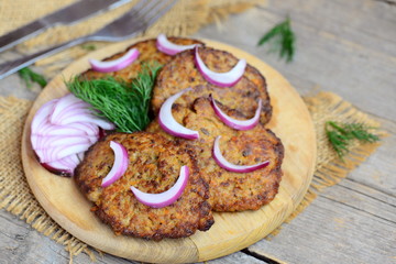 Homemade fried cutlets from chicken liver mince, carrot and onion. Quick easy liver cutlets on a wooden chopping board. Closeup