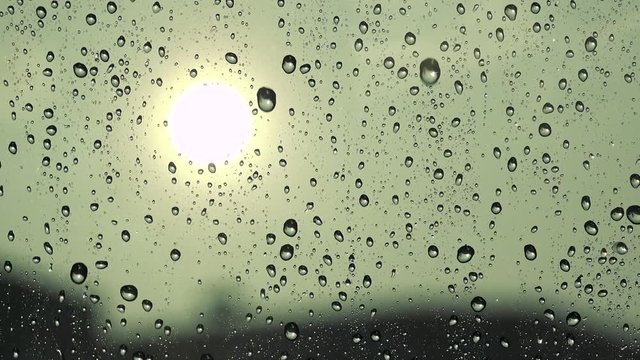 Rain drops fall on the window - sun in the background