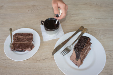 Female hands holding cup of coffee and cookies on wooden table
