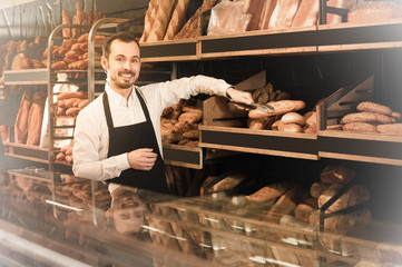Obraz na płótnie Canvas Assistant baker offers a variety of delicious bread