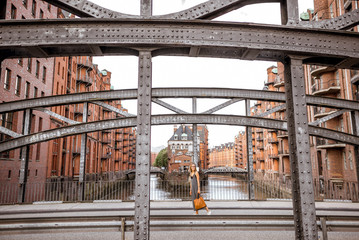 Beautiful iron bridge with woman walking in Speicherstadt, historic warehouse district in Hamburg, Germany