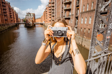 Young woman tourist photographing beautiful view on the Speicherstadt, historic warehouse district...