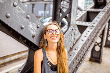 Lifestyle portrait of a young stylish smiling woman outdoors on the old iron bridge