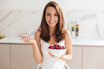 Happy smiling woman holding bowl with fresh berries