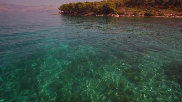 4K AERIAL: Happy young woman in bikini lying on inflatable air bed mattress in adriatic on her fun summer vacation