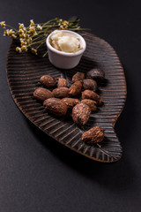 Shea butter and shea butter nuts on black background
