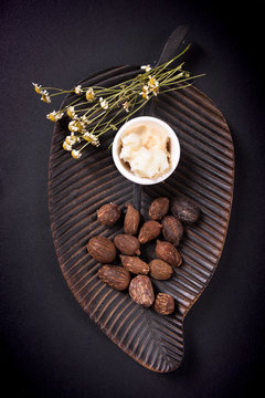 Shea butter and shea butter nuts on black background