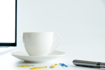 Coffee Cup and computer desktop on white office desk table with a silver pen and note for working in the morning with closeup view and copy space conecpt.