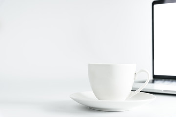 Coffee Cup and computer desktop on white office desk table with a silver pen and note for working in the morning with closeup view and copy space conecpt.