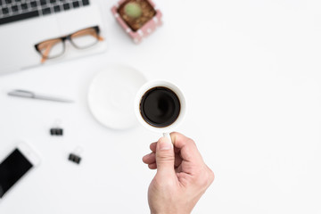 Businessman has holding black coffee cup to drinking on hard working in the morning. Businessman working with black coffee and computer on desk from tabletop view concept.