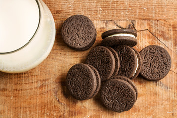 Vaso de leche con galletas de chocolate sobre una mesa de madera. Vista superior