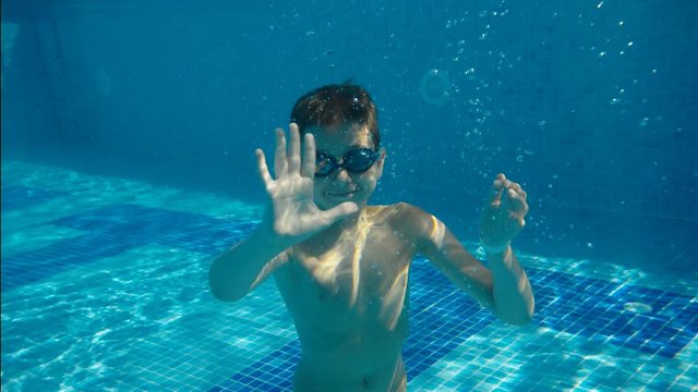 the boy waved his hand underwater in the pool