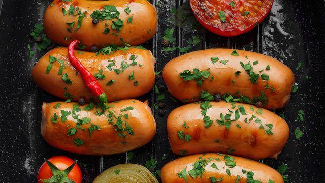 Fried sausages with herbs and vegetables in grill pan