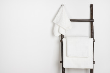 Spa towels hanging on vintage wooden stepladder isolated on white