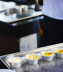 The cook caramelizes sugar on cream brule. Flaming