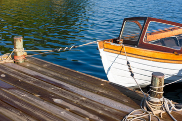 Front of vintage motorboat tied to a pier in calm water.