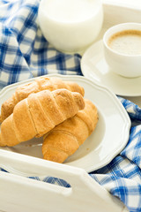 Traditional breakfast with fresh croissants, milk and espresso on white wooden salver . Selective focus