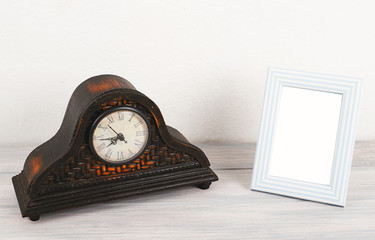 Photo frames next to wooden clock on wooden table. Decor.