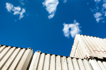Low angle view of white pallet wide containers against blue sky with white clouds.