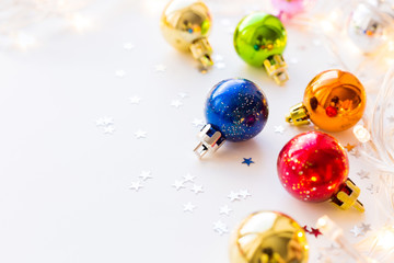 Christmas and New Year background with colorful decorative balls for Christmas tree with light bulbs and confetti. Place for text.