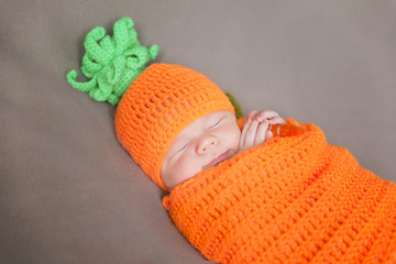 Newborn baby wearing a knitted carrot or pumpkin hat
