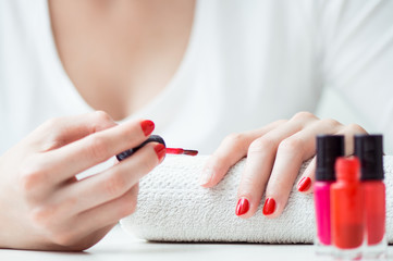 Close-up of red nail polish drop  wih woman nails on backbround