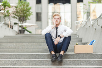 Unfair ginger young adult worker sit on stairs and wondering.
