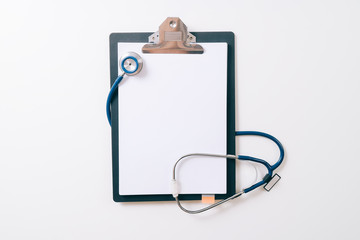 Fototapeta na wymiar blank stethoscope and gray clipboard on white desk background