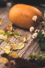 Autumn still life: pumpkin and autumn leaves on a wooden background.