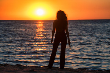 Silhouette young woman on the beach at sunset