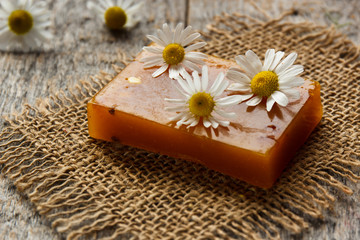 Obraz na płótnie Canvas Natural handmade soap and chamomile on wooden background. Selective focus.