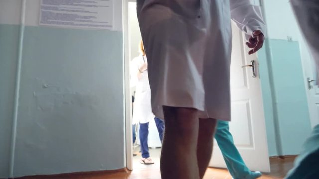 Two male caucasian doctors come out cabinet and view mri picture. Two nurses followed by the physicians. Low angle of view