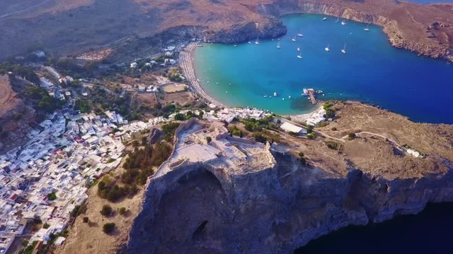 Aerial drone video of iconic ancient Acropolis and village of Lindos, Rodos island, Aegean, Dodecanese, Greece