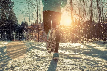 Foto auf Acrylglas Sport Frau, die im verschneiten Winter unter Sonnenlicht läuft.