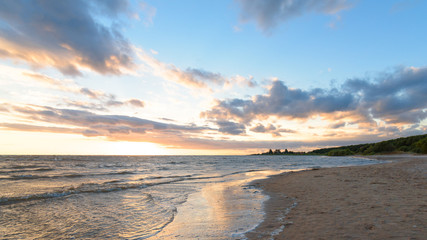 Fototapeta premium Quiet empty beach at sunset on a background of blue sky with clouds