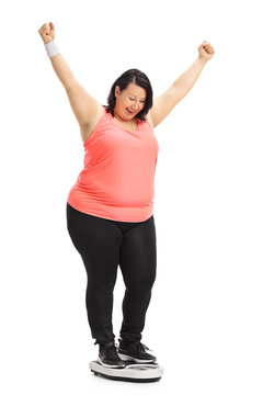 Overweight woman on a weight scale gesturing happiness