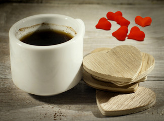 Close up cup of coffee with wooden hearts and red hearts