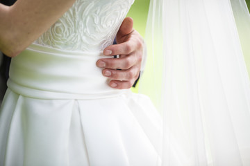groom embraces the bride with wedding bouquet. the hands of the newlyweds