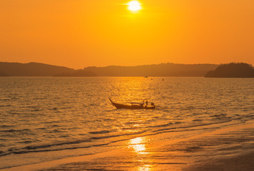             Longtail boat sailing in tropical andaman sea during sunset time at Krabi, Thailand 