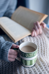 a person is reading a book and drinking coffee