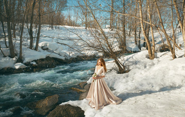 Beautiful young girl in a chic dress in the nature next to the river